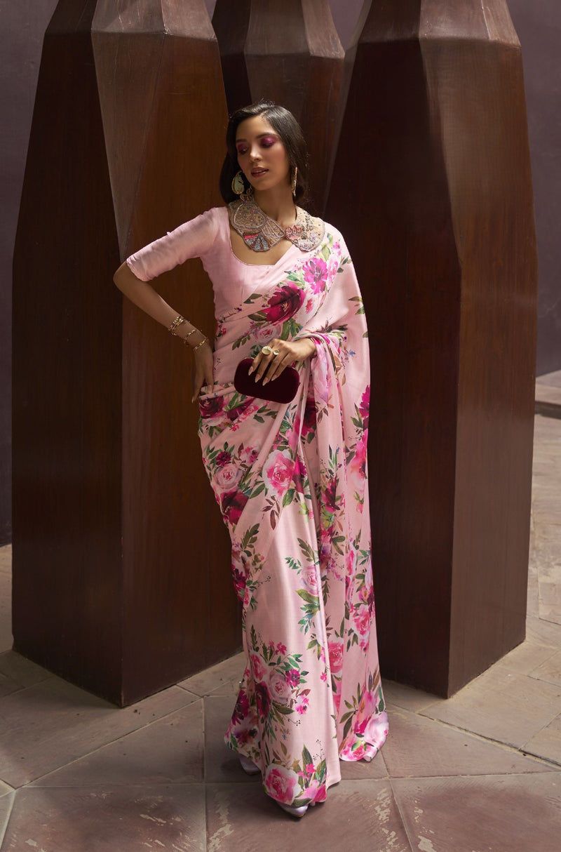 Light pink silk saree with vibrant floral print—green accents and glossy finish for soft festive styling