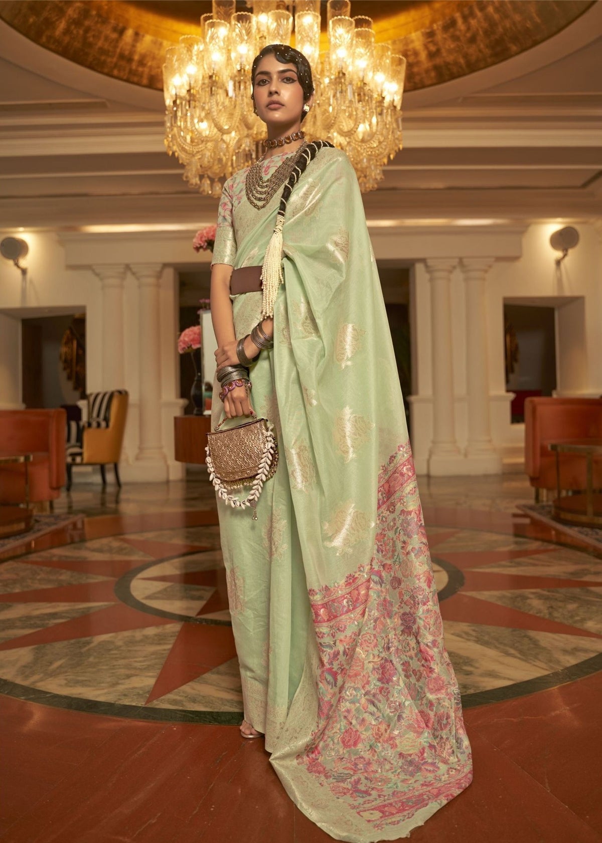 Light green silk saree with pink and gold floral embroidery and a soft, elegant designer drape.