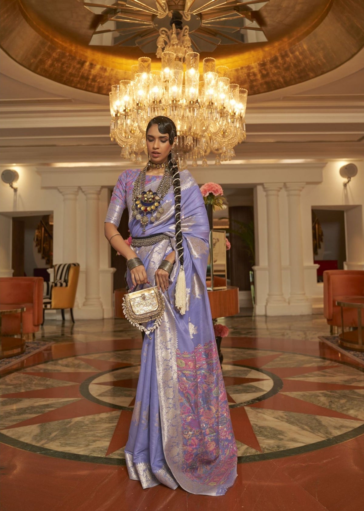 Lavender silk saree with silver zari detailing and vibrant floral border accents.