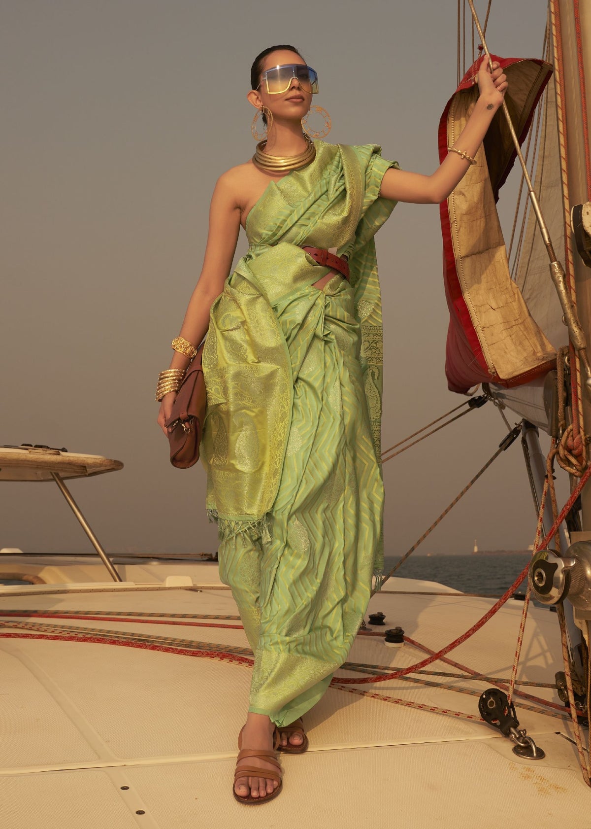 “Light green silk saree with detailed woven motifs and modern belt styling.”
