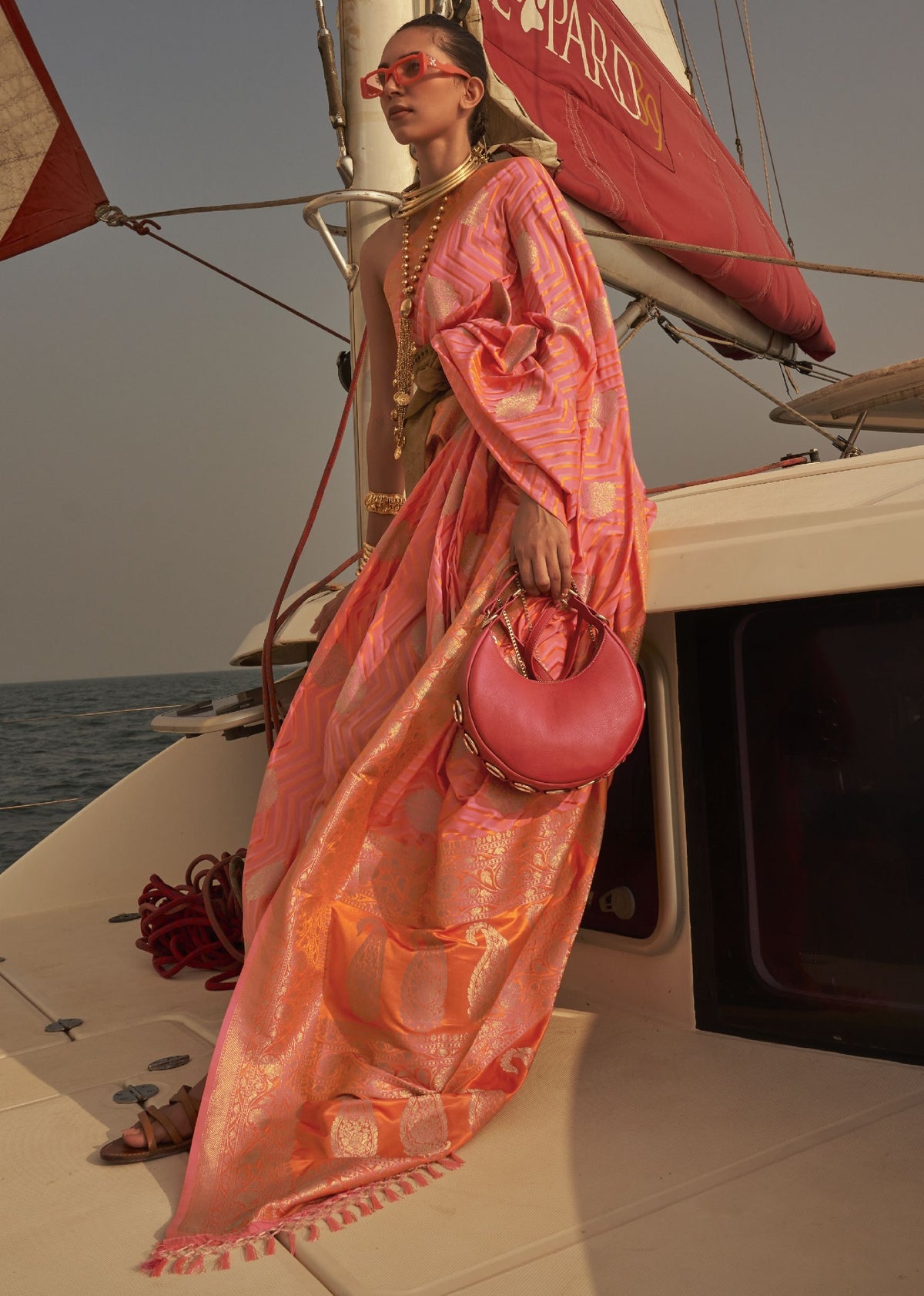 “Pink and orange saree with gold woven detailing and traditional festive motifs.”
