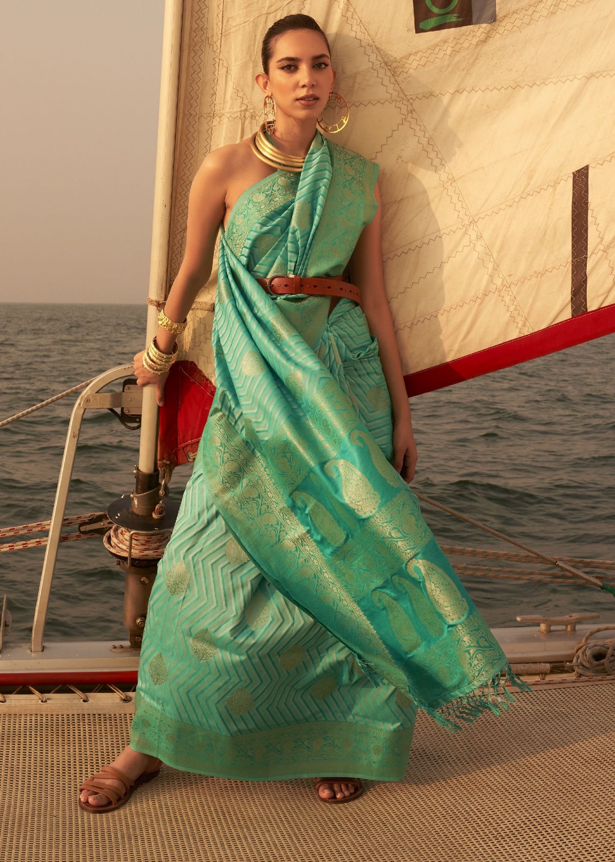 “Turquoise saree with gold peacock motifs and geometric woven detailing.”