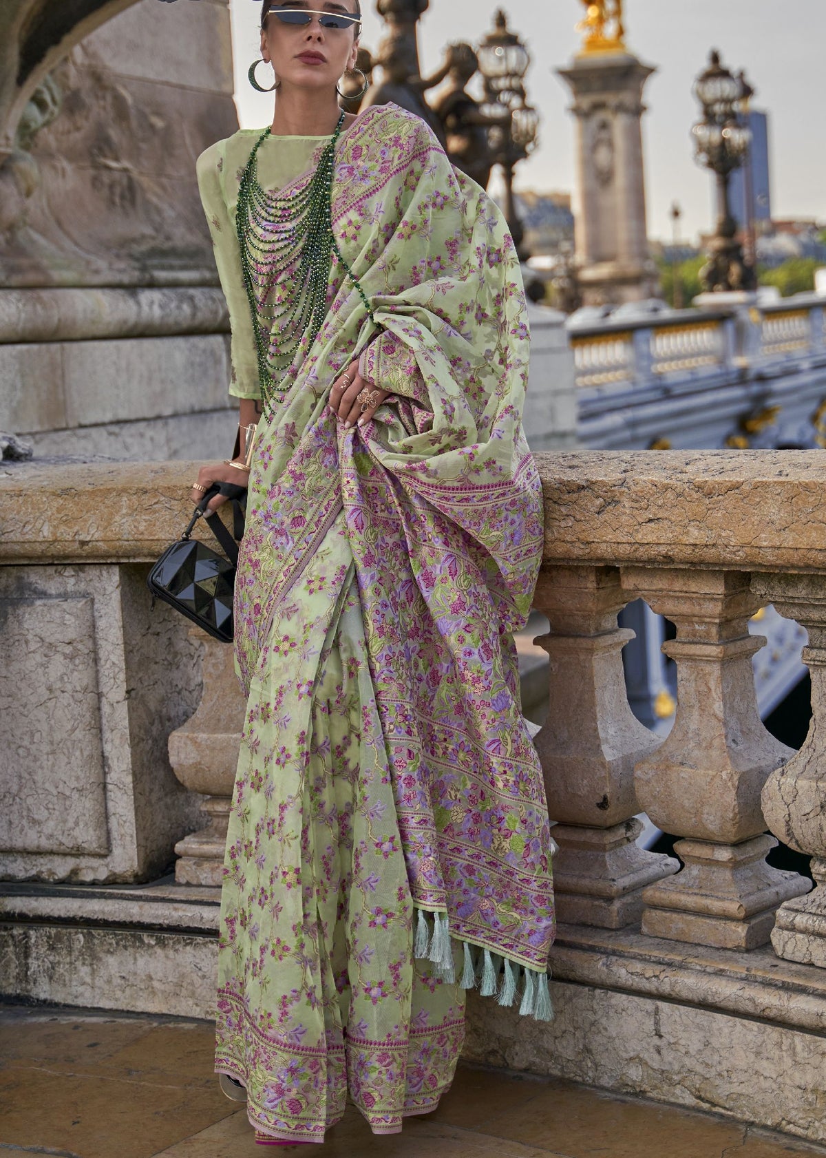 Light green saree featuring pink floral motifs and a purple‑gold traditional border.