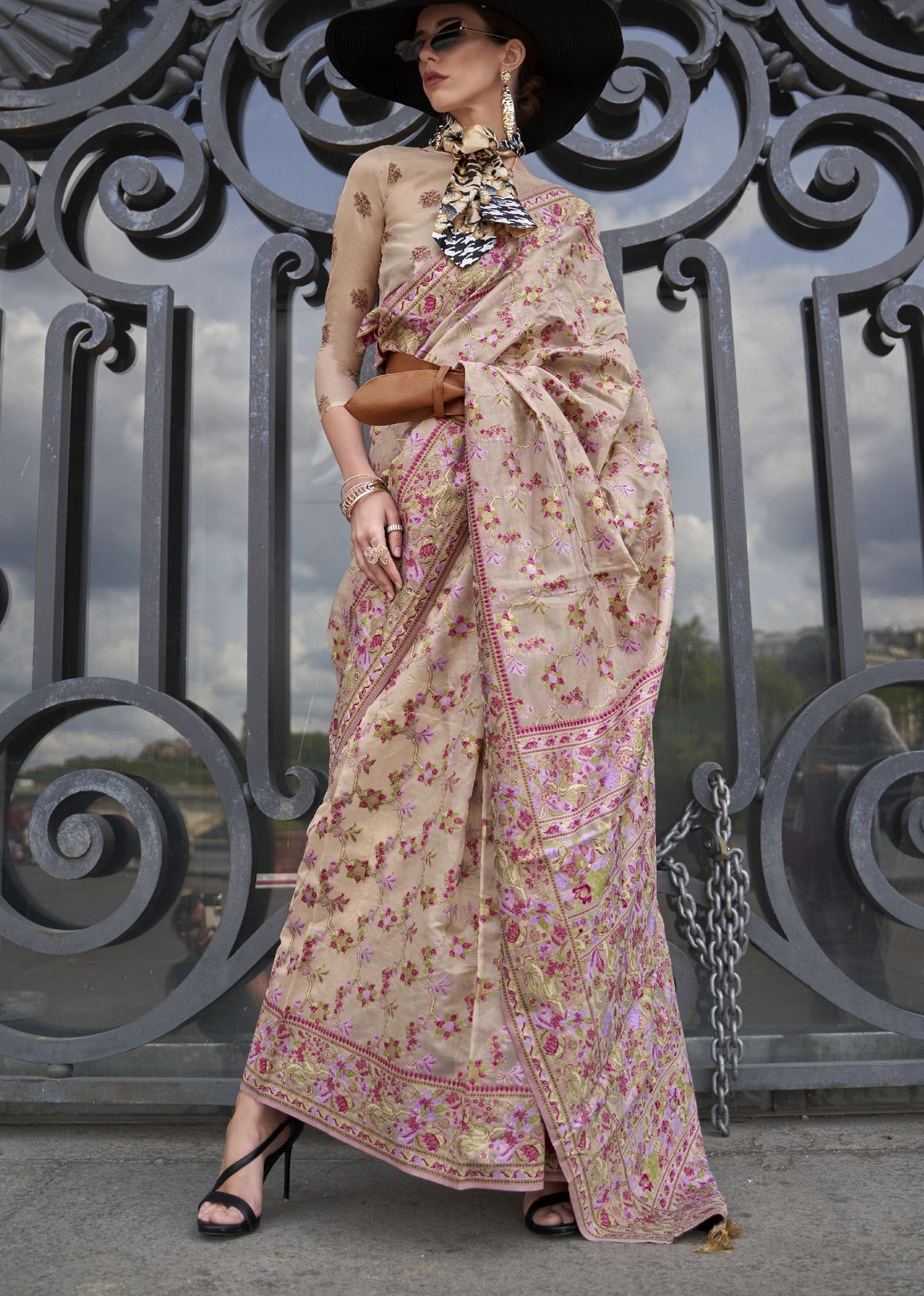 Beige saree with delicate pink, green and gold floral embroidery and a soft shimmer finish.