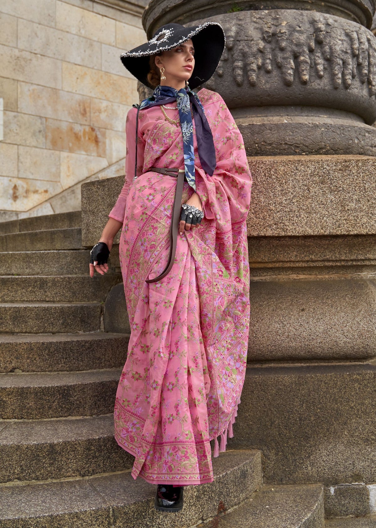 Pink saree with intricate floral patterns in multiple colours and a traditional woven border