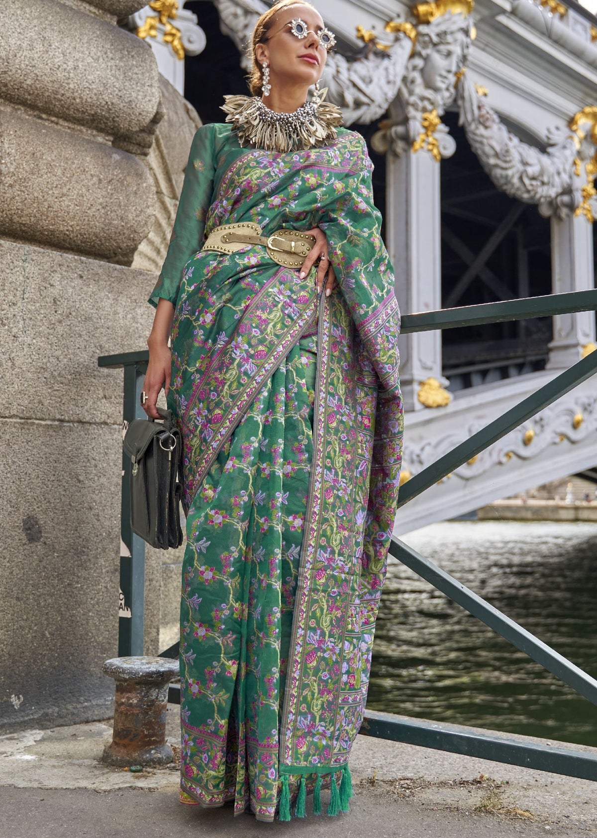  Vibrant green saree with purple, pink and gold floral motifs and a detailed embroidered border.