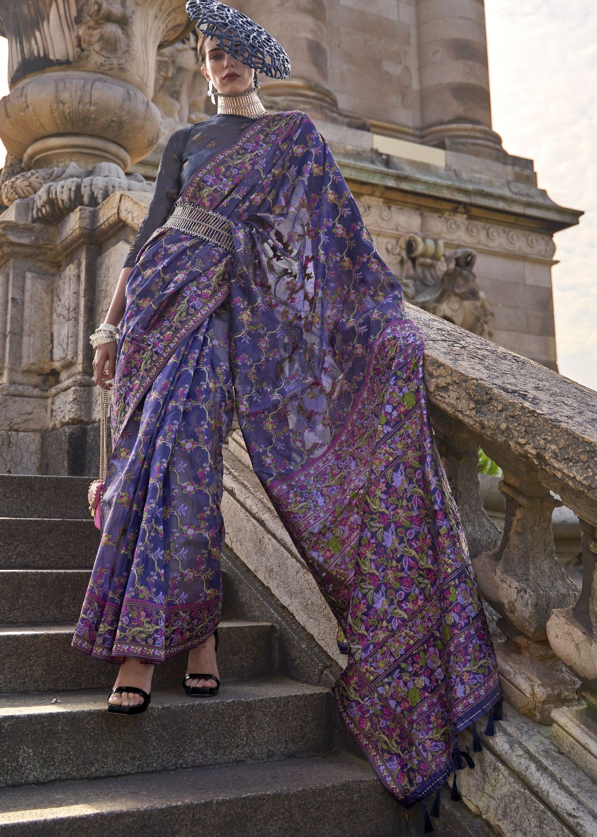 Deep purple saree with green, pink and gold floral designs and a rich, ornate border.