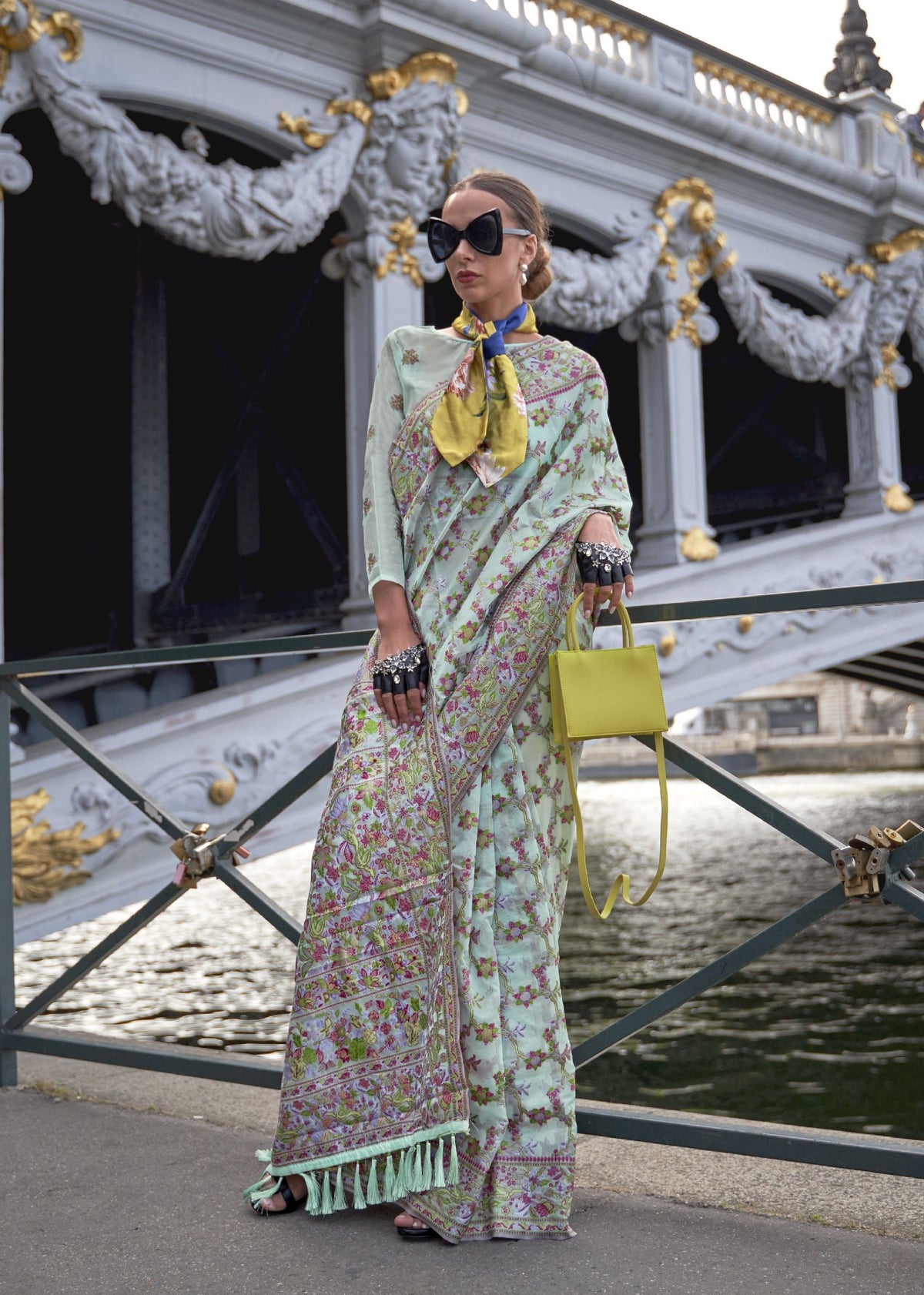 Pastel green saree with pink floral embroidery and a tasselled decorative border.