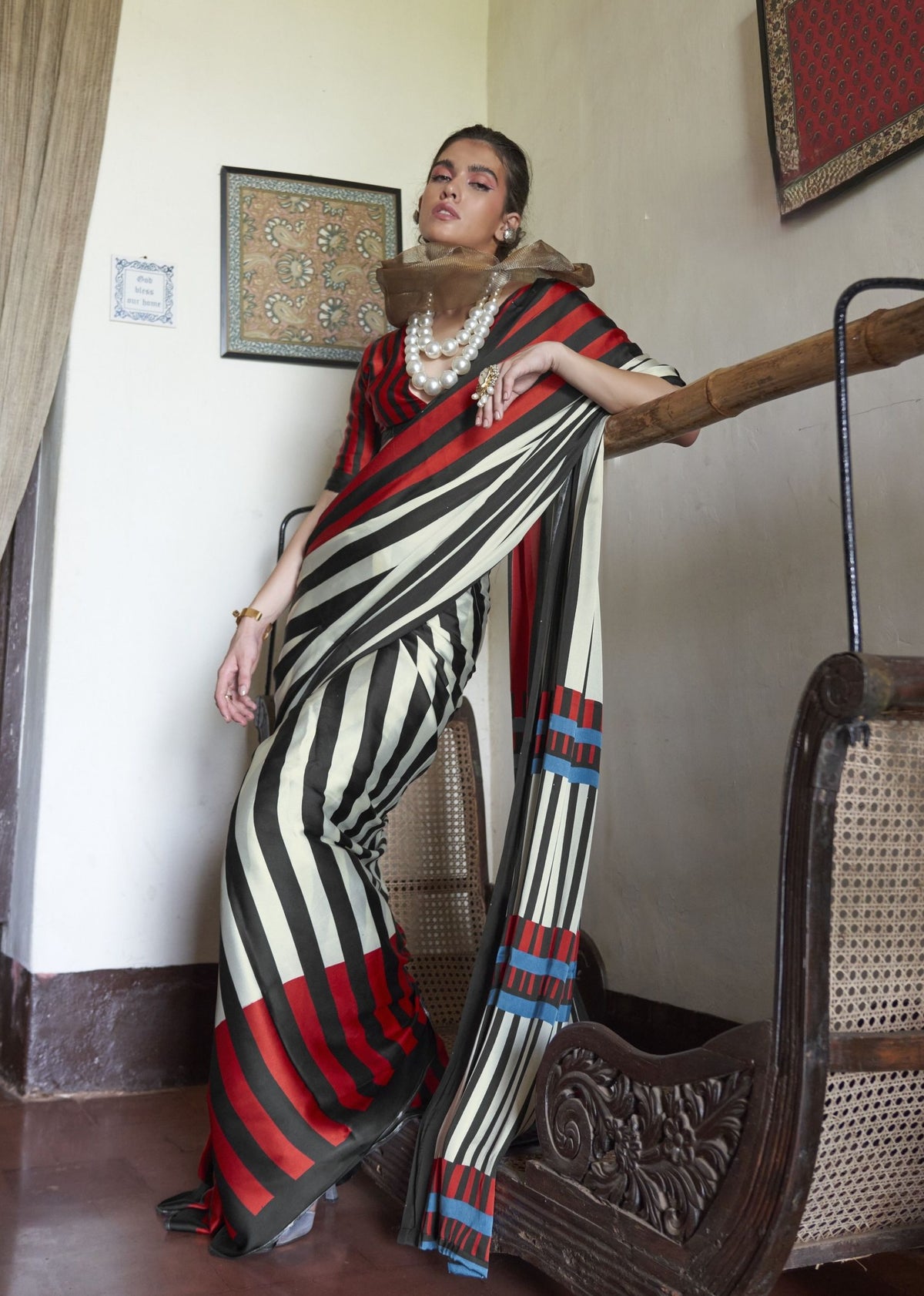 Woman in a black, white, and red striped saree standing indoors. Kaalin satin saree - front view