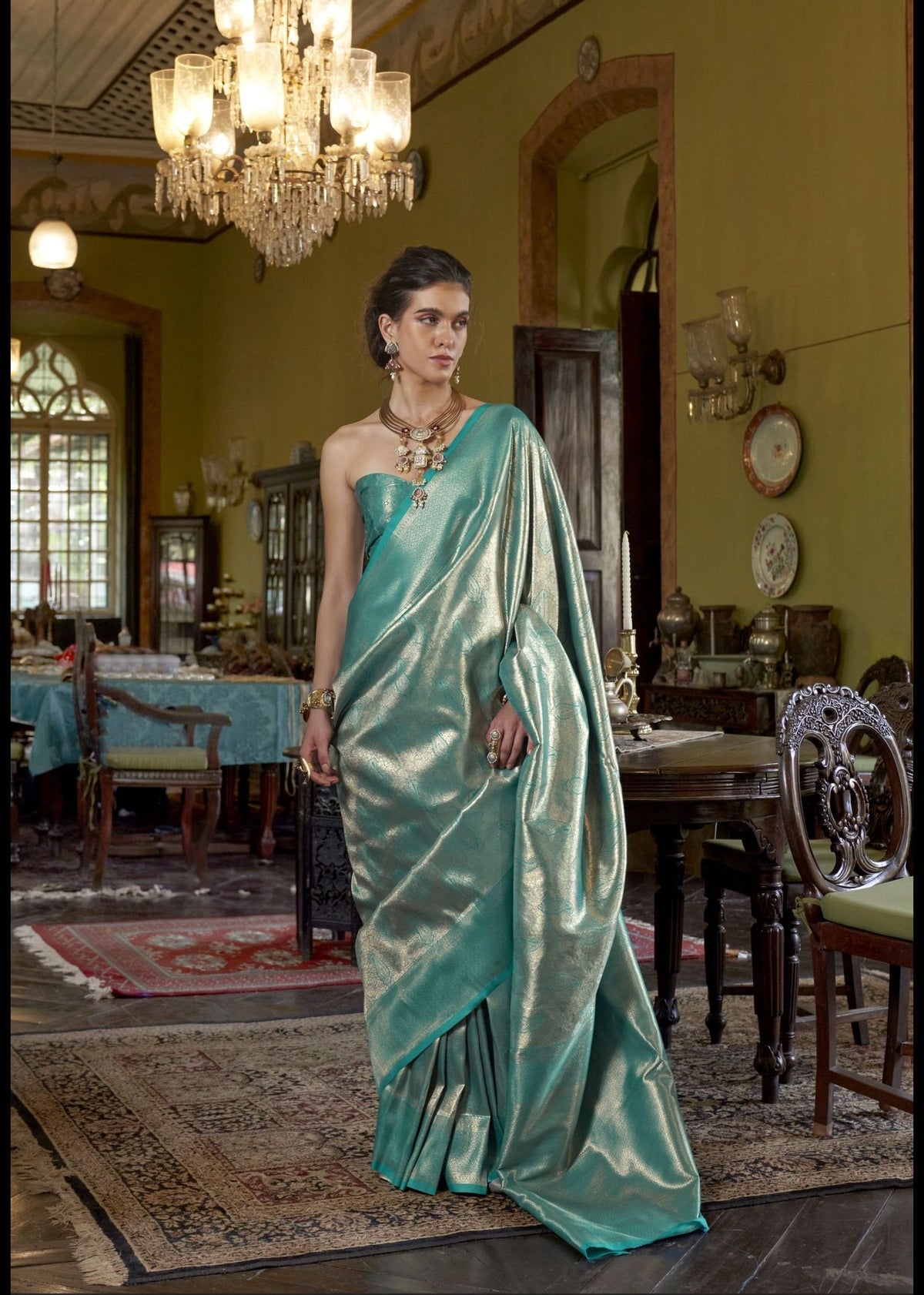 Teal Kanjivaram silk saree with gold zari motifs and a classic handwoven border in traditional Kanchipuram style.